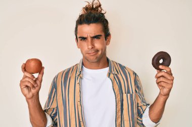 Genç İspanyol adam kırmızı elma ve donut tutuyordu. Hiçbir şeyden haberi yoktu ve kafası karışmıştı. şüphe kavramı. 