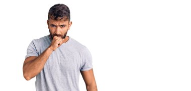 Günlük kıyafetler giyen genç İspanyol adam kendini iyi hissetmiyor ve soğuk algınlığı veya bronşitin belirtisi olarak öksürüyor. sağlık hizmeti kavramı. 