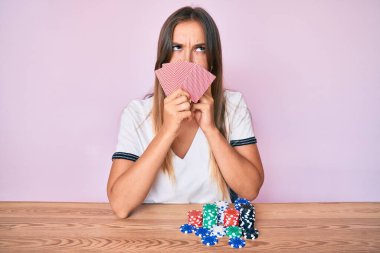 Kafkasyalı güzel bir kadın poker oynuyor. Yüzünde kartlarla kumar oynuyor. Ciddi bir yüz ifadesi var. 