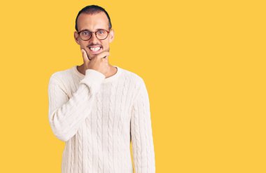 Gündelik kıyafetler ve gözlük takan genç yakışıklı adam kameraya kendinden emin bir şekilde bakıyor kollarını kavuşturmuş ve çenesini kaldırmış gülümsüyor. Olumlu düşünmek. 