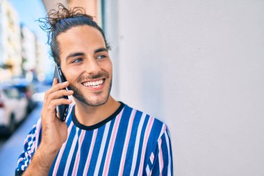 Genç İspanyol adam gülümsüyor. Şehirdeki akıllı telefondan konuşuyor..