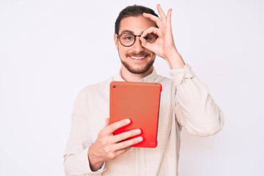 Genç yakışıklı adam dokunmatik ped cihazı kullanıyor. Gülümsüyor, mutlu mesut imzalıyor. Elleri gözlerinde parmaklarından bakıyor. 