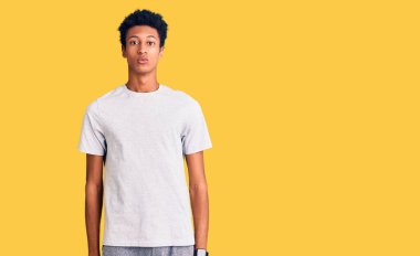 Gündelik kıyafetler giyen genç Afro-Amerikan adam yüzünde ciddi bir ifadeyle rahatlamış. Basit ve doğal bir şekilde kameraya bakıyorsun.. 