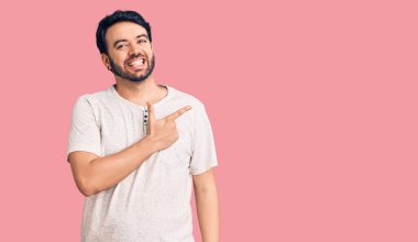 Yüzünde mutlu ve doğal bir ifade olan, elleri ve parmaklarıyla işaret eden, güler yüzlü, gündelik kıyafetler giyen genç İspanyol adam. 