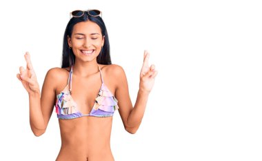 Bikini giyen ve güneş gözlüğü takan genç, güzel bir Latin kız umut ve gözlerin kapalı bir şekilde gülümseyerek el sallıyor. Şans ve batıl inançlar. 
