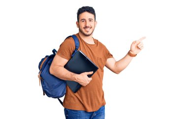 Sırt çantası taşıyan İspanyol bir genç. Sırtında bir klasör var. Gülümsüyor. 