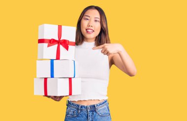 Genç, güzel Çinli bir kız elinde hediyeyle mutlu bir şekilde gülümsüyor. 