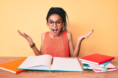 Okul için örgü ören Afrikalı Amerikalı kız çocuğu zaferi mutlu bir gülümsemeyle ve ellerini kaldırarak kutluyor. 