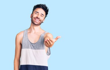 Gündelik kıyafetler giyen genç İspanyol adam dostça bir selamlama ve hoş geldin hediyesi olarak el sıkışmayı sunuyor. başarılı iş. 