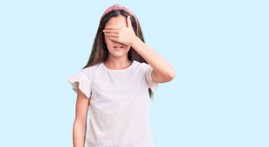 Latin kökenli tatlı bir kız. Günlük beyaz tişörtler giyiyor. Gözleri elle örtüyor, ciddi ve üzgün görünüyor. Görme, saklama ve reddetme konsepti 