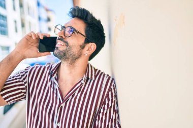 Sakallı, yakışıklı, dışarıda mutlu bir şekilde gülümseyen telefonda konuşan genç bir İspanyol.