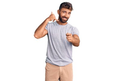 Gündelik kıyafetler giyen, gülümseyen, telefonda konuşan ve seni işaret eden İspanyol bir genç. Ara beni.. 