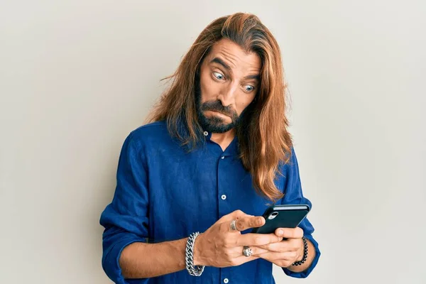 Atraktivní Muž Dlouhými Vlasy Vousy Pomocí Smartphonu Šokovém Obličeji Vypadá — Stock fotografie