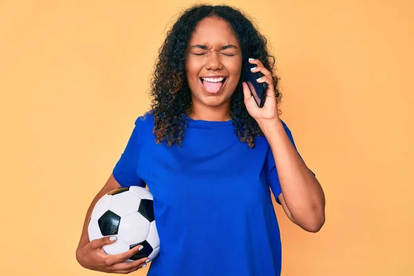 Jovem Afro Americana Segurando Bola Futebol Falando Smartphone Furando Língua — Fotografia de Stock