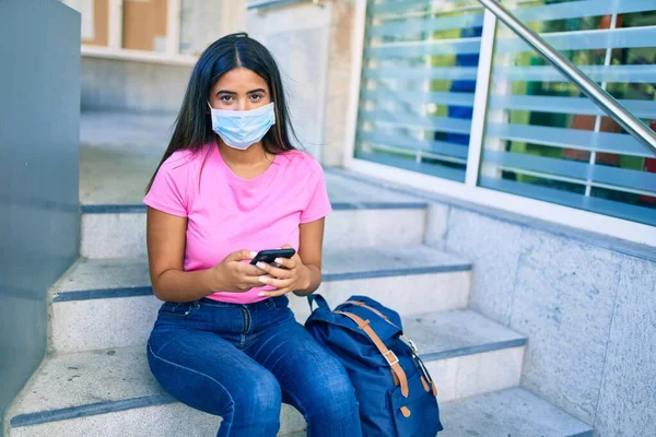 Νεαρή Λατίνα Μαθήτρια Που Φοράει Ιατρική Μάσκα Χρησιμοποιώντας Smartphone Στην — Φωτογραφία Αρχείου