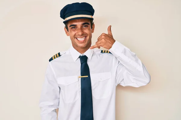 Junger Hispanischer Mann Flugzeugpilotenuniform Lächelt Und Macht Telefongesten Mit Händen — Stockfoto
