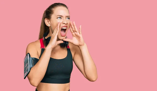 Hermosa Mujer Rubia Vistiendo Ropa Gimnasio Usando Auriculares Gritando Enojado — Foto de Stock