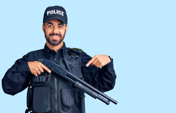 Joven Hispano Vistiendo Uniforme Policial Sosteniendo Escopeta Sonriendo Feliz Señalando — Foto de Stock