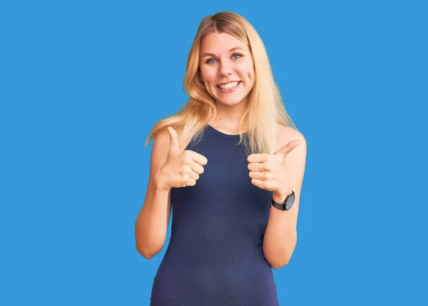 Young beautiful blonde woman wearing casual dress success sign doing positive gesture with hand, thumbs up smiling and happy. cheerful expression and winner gesture.