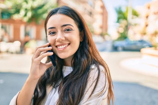 若いヒスパニック系の女性は 市内のスマートフォンで幸せな話を笑って — ストック写真