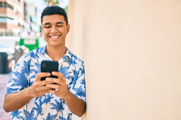 街の通りにある壁にスマートフォンをもたせて夏風を身に着けている若いアラブ観光客の男 — ストック写真