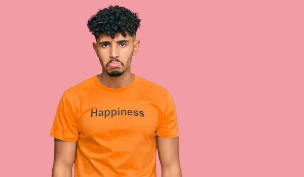 年轻的阿拉伯男子穿着印有快乐信息的T恤衫 忧心忡忡 哭哭啼啼 非常害怕 悲伤的表情 — 图库照片