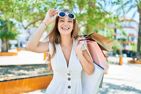 Νεαρή Ξανθιά Γυναίκα Χαμογελά Ευτυχισμένη Κρατώντας Τσάντες Ψώνια Στο Δρόμο — Φωτογραφία Αρχείου