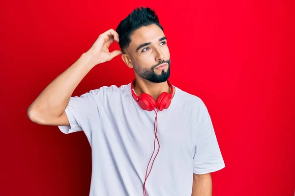 Jovem Com Barba Ouvindo Música Usando Fones Ouvido Confundir Perguntando — Fotografia de Stock
