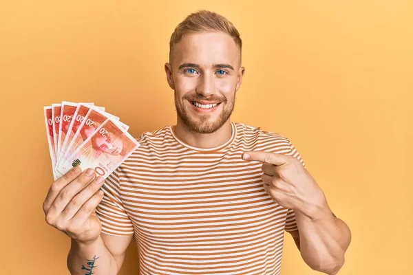 Joven Hombre Caucásico Sosteniendo Shekels Israelíes Billetes Sonriendo Feliz Señalando —  Fotos de Stock