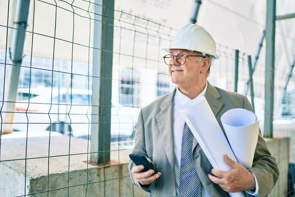 Senior Uomo Architetto Dai Capelli Grigi Possesso Cianografie Utilizzando Smartphone — Foto Stock