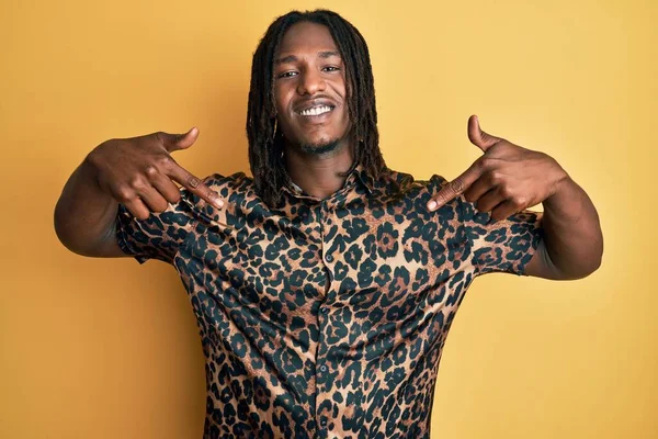 African american man with braids wearing leopard animal print shirt looking confident with smile on face, pointing oneself with fingers proud and happy.
