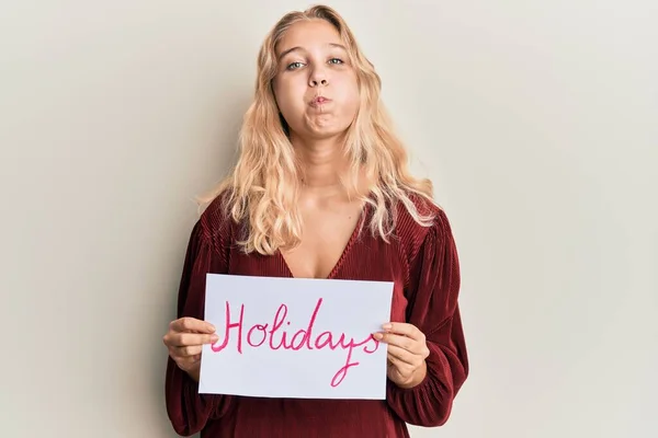 Menina Loira Jovem Segurando Feriados Banner Mensagem Soprando Bochechas Com — Fotografia de Stock