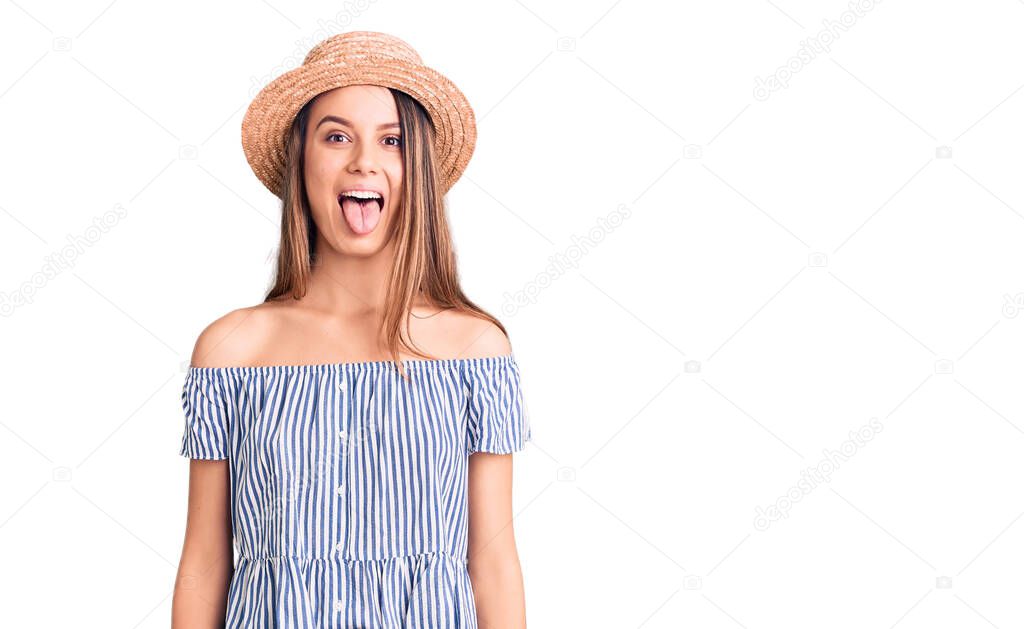 Young beautiful girl wearing hat and t shirt sticking tongue out happy with funny expression. emotion concept. 