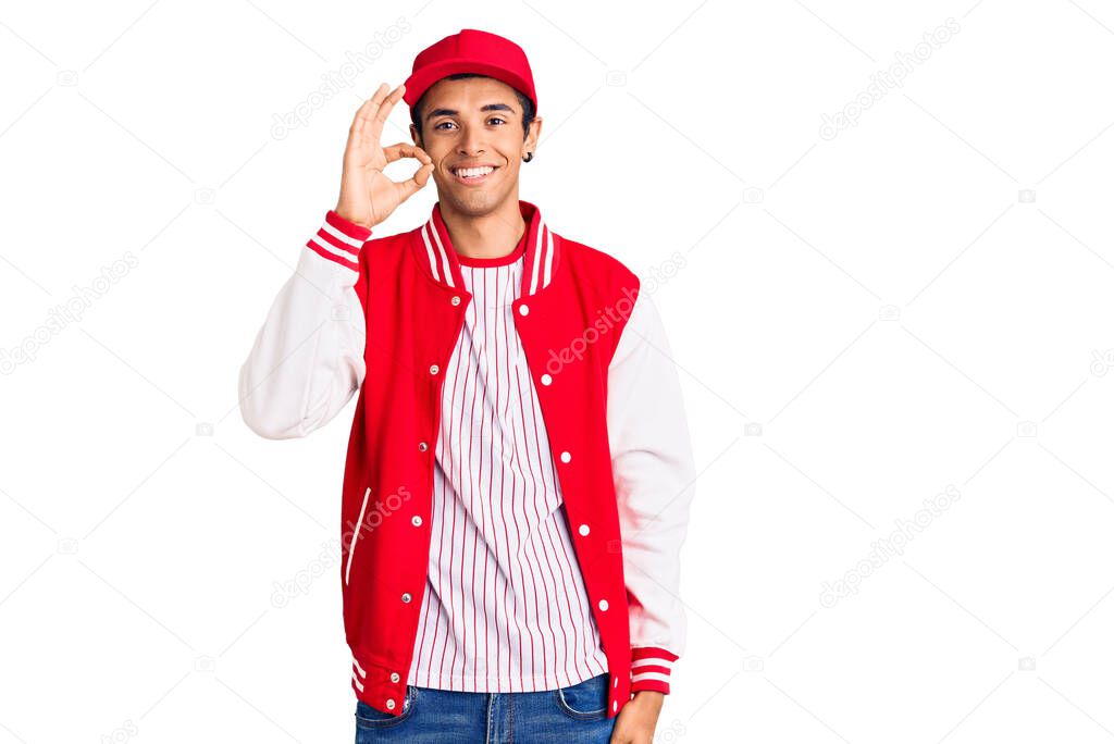 Young african amercian man wearing baseball uniform smiling positive doing ok sign with hand and fingers. successful expression. 