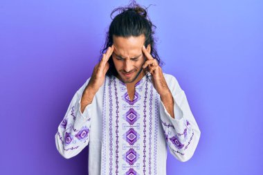 Uzun saçlı, bohem tişörtlü, başı ağrıyan genç ve yakışıklı bir adam. Stres yüzünden. migren ağrısı. 