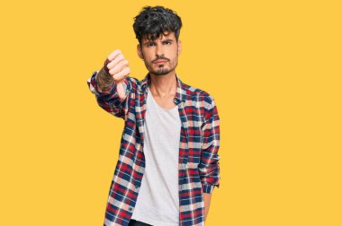 Gündelik kıyafetler giyen genç İspanyol adam mutsuz görünüyor ve reddediliyor ve olumsuz bir hareket yapıyor. kötü ifade. 