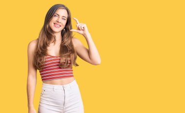 Güzel, beyaz, sıradan kıyafetler giyen, gülümseyen, kendine güvenen, el hareketi yapan, parmaklarıyla işaret yapan, kameraya bakan genç bir kadın. ölçüm kavramı. 