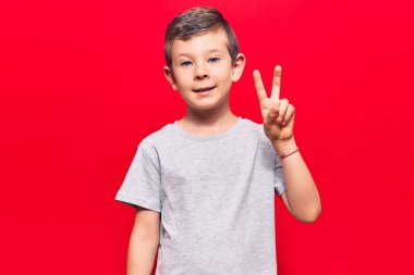 Gayri resmi giyinen, gülen, kameraya göz kırpan, zafer işareti yapan sevimli sarışın çocuk. İki numara.. 