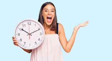 Genç İspanyol kadın büyük bir saat tutuyor zaferi mutlu bir gülümsemeyle kutluyor ve kazanan yüz ifadesi kaldırıyor. 