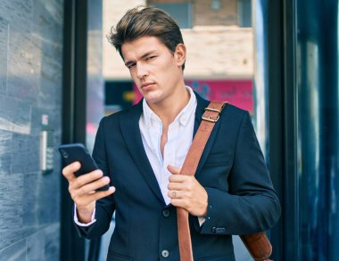 Şehirdeki akıllı telefonu ciddi bir ifadeyle kullanan genç beyaz iş adamı..