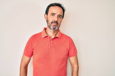 Orta yaşlı İspanyol bir adam gündelik kıyafetler giyiyor ve yüzünde ciddi bir ifadeyle rahatlıyor. Basit ve doğal bir şekilde kameraya bakıyorsun.. 