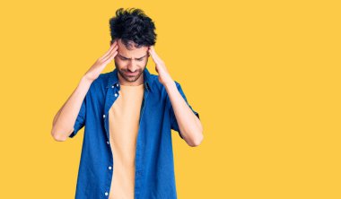 Stres yüzünden başı ağrıyan Latin kökenli genç bir adam günlük kıyafetler giyiyor. migren ağrısı. 