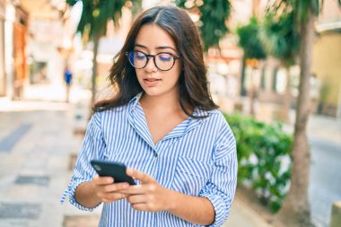 Şehirde akıllı telefon kullanan ciddi bir suratı olan genç İspanyol iş kadını..