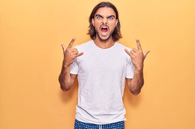 Genç, yakışıklı, günlük kıyafetler giymiş, çılgın bir ifadeyle bağıran, elleri havada rock sembolü yapan bir adam. Müzik yıldızı. ağır kavram. 