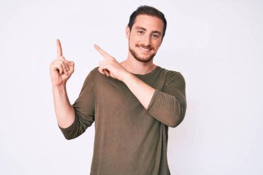 Gündelik kıyafetler giyen, gülümseyen ve kameraya bakan genç, yakışıklı bir adam.. 