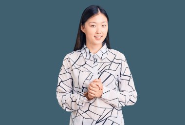 Genç, güzel, Çinli bir kadın, elleri bağlı, rahat ve neşeli bir şekilde gülümsüyor. Başarı ve iyimserlik 