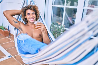 Genç İspanyol adam terasta hamakta uzanmış bira içerek rahatladı..