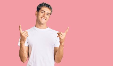 Gündelik beyaz tişört giyen, kendine güvenen, farklı yönleri gösteren genç, yakışıklı bir adam. reklam için kopyalama alanı 