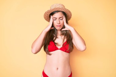 Güzel, beyaz bir kadın bikini giyiyor ve kafasında şapkası olan bir kadın. Stres yüzünden başı ağrıyor. migren ağrısı. 