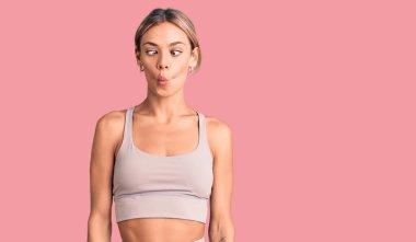 Güzel beyaz kadın spor giysisi giyiyor, dudaklarıyla balık suratı yapıyor, çılgınca ve komik hareketler yapıyor. Komik ifade. 